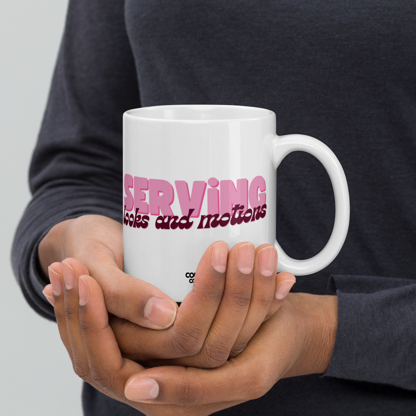 a white, 11oz mug featuring the words "serving looks and motions" in pink and burgundy letters.