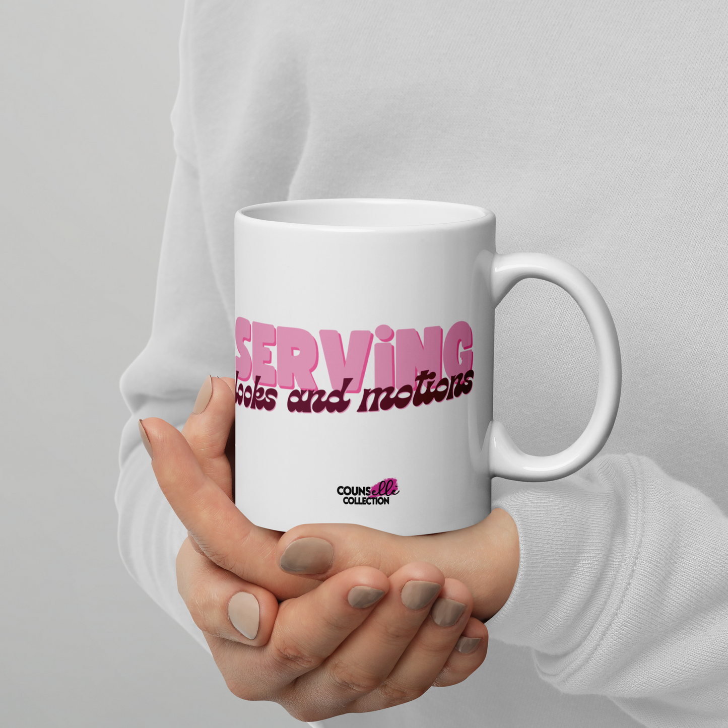 a white, 11oz mug featuring the words "serving looks and motions" in pink and burgundy letters.