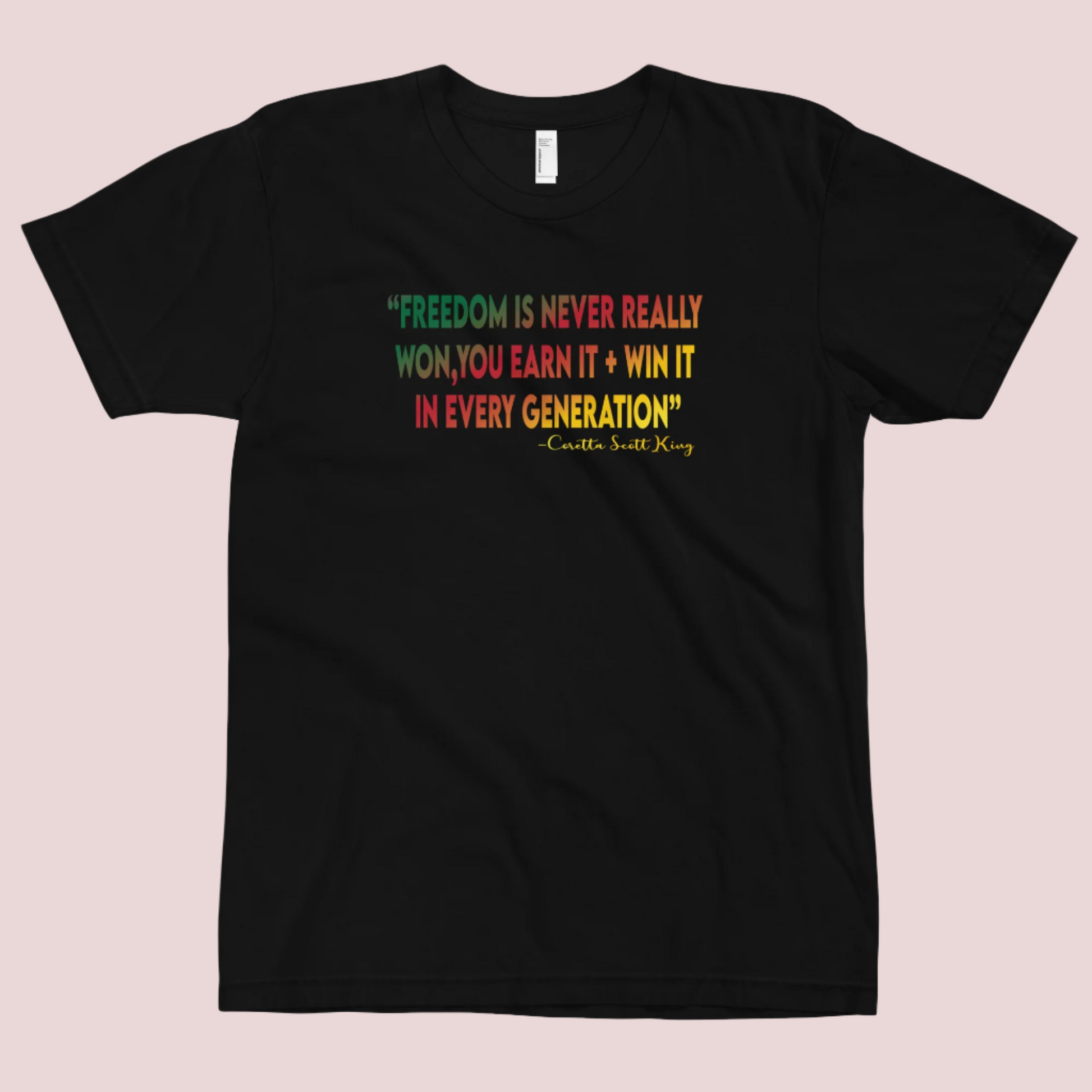  A red roundneck tee featuring the quote "FREEDOM IS NEVER REALLY WON, YOU EARN IT + WIN IT In EVERY GENERATION" followed by the text "-Carlotta Scott King", all are written in green, red, and yellow striped font. 