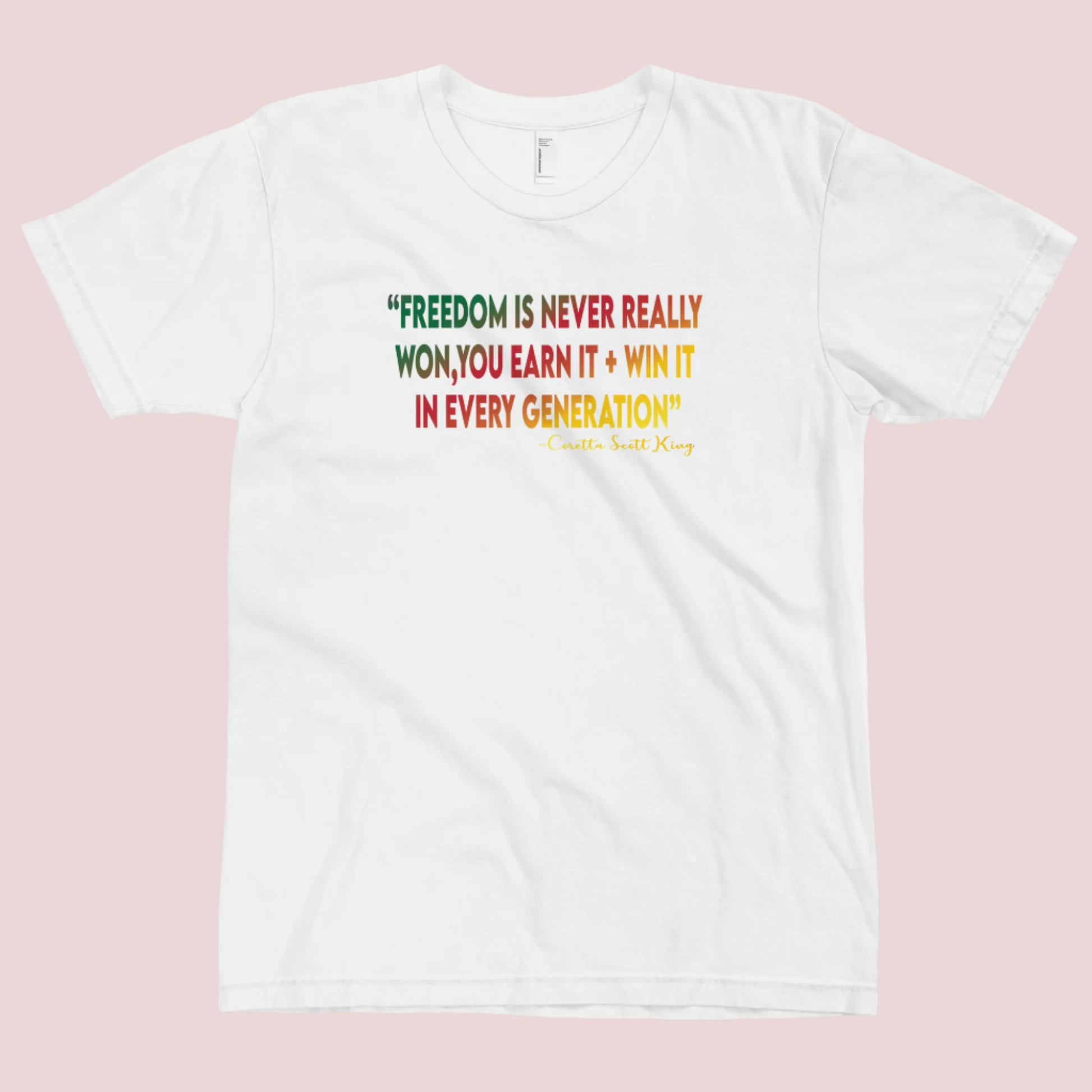 A white roundneck tee featuring the quote "FREEDOM IS NEVER REALLY WON, YOU EARN IT + WIN IT In EVERY GENERATION" followed by the text "-Carlotta Scott King", all are written in green, red, and yellow striped font. 