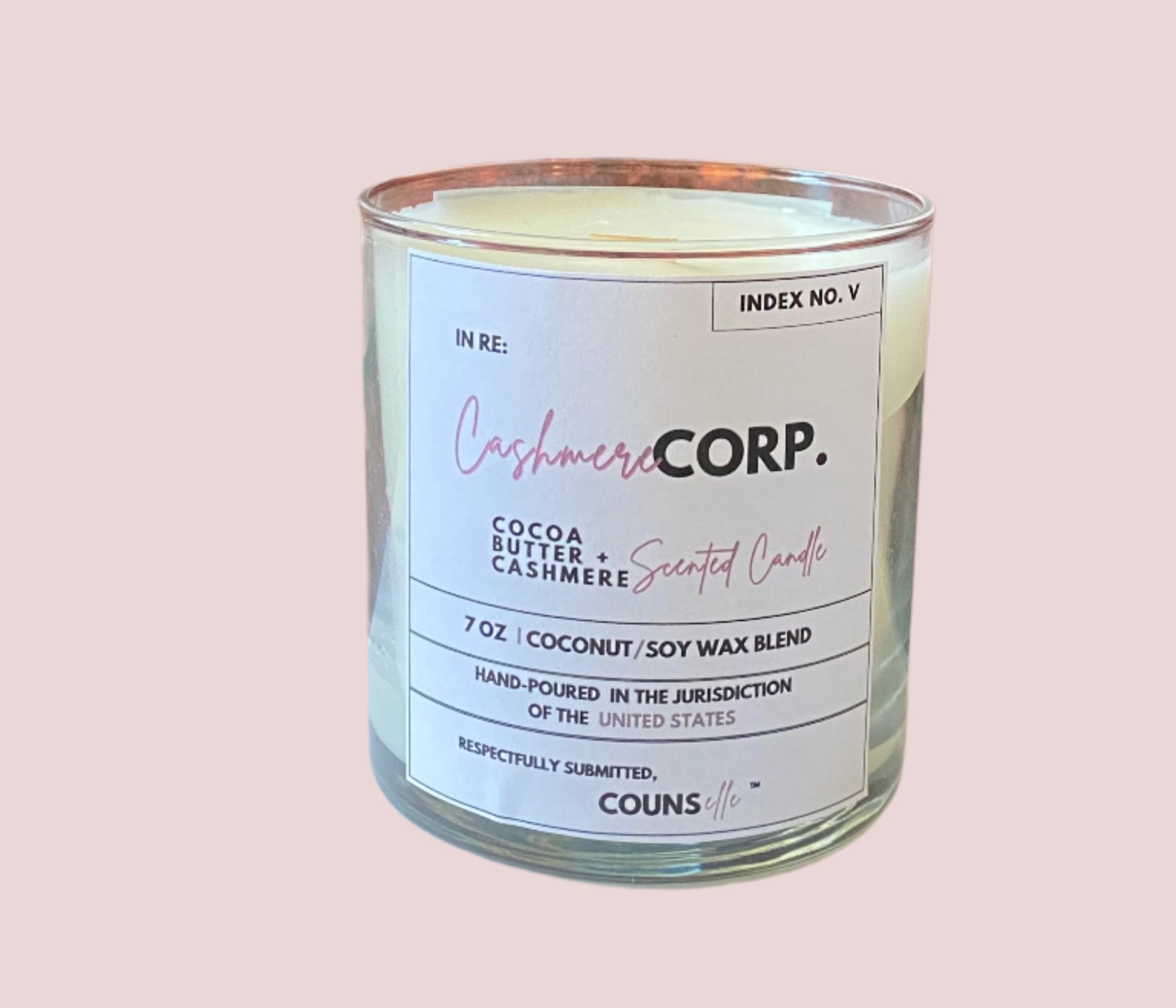 A candle in a glass container with a white label featuring the text "INDEX NO. V", "IN RE:", "CASHMERE CORP.", "COCOA BUTTER + CASHMERE SCENTED CANDLE", "7 oz", "COCONUT/SOY WAX BLEND", "HAND-POURED IN THE JURISDICTION OF THE UNITED STATES", "RESPECTFULLY SUBMITTED", with the counsellecollection logo at the bottom of the design