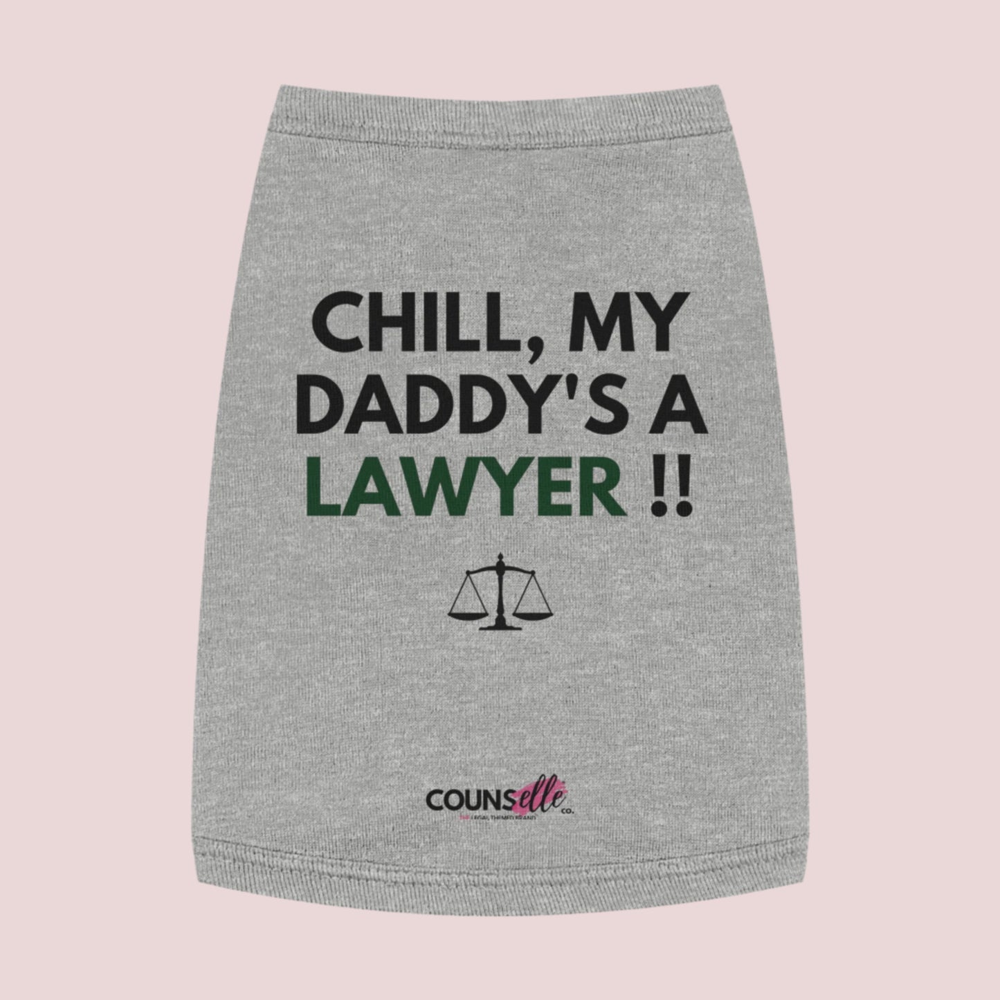  A grey pet tee featuring the quote "Chill, my daddy's a lawyer" in uppercase text, an illustration of justice scales below the text and the counsellecollection logo near the hem.