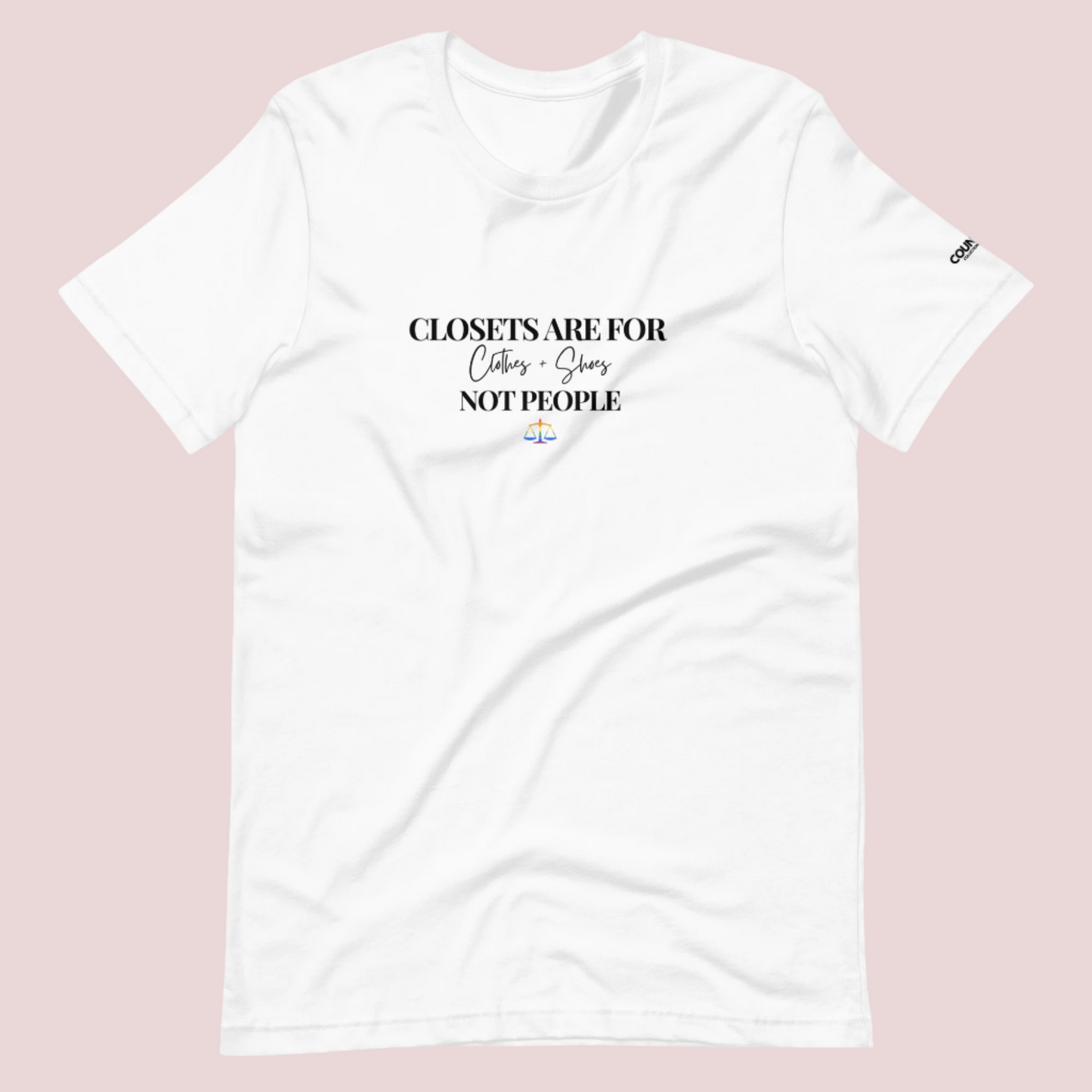 A white crewneck tee with the text "CLOSETS ARE FOR CLOTHES + SHOES NOT PEOPLE" in black font, with an illustration of a rainbow justice scales underneath. The counsellecollection logo is seen on the left sleeve.