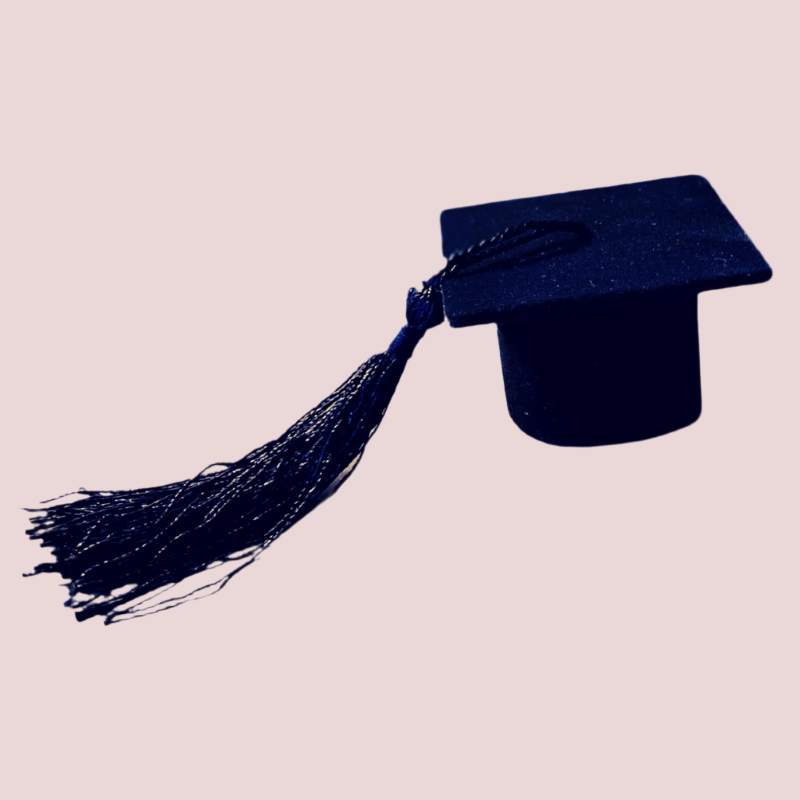 A black jewelry box in the shape of a graduation cap with a black tassel on the side.