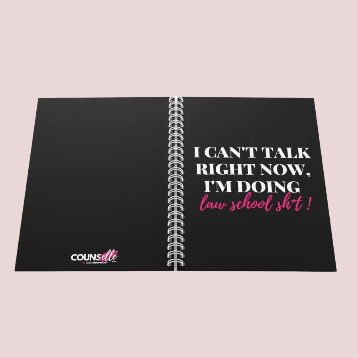 A black wire bound notebook with the text "I can't talk right now, I'm doing law school sh*t" on the cover and the counsellecollection logo at the bottom center part of the back cover.