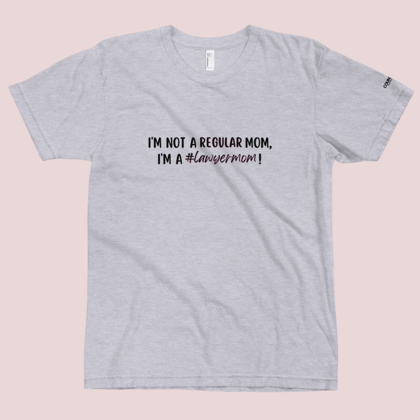 A heather grey round-neck tee with the text "I'M NOT A REGULAR MOM, I'M A #LawyerMom!" in black" text and the counsellecollection logo on the left sleeve.