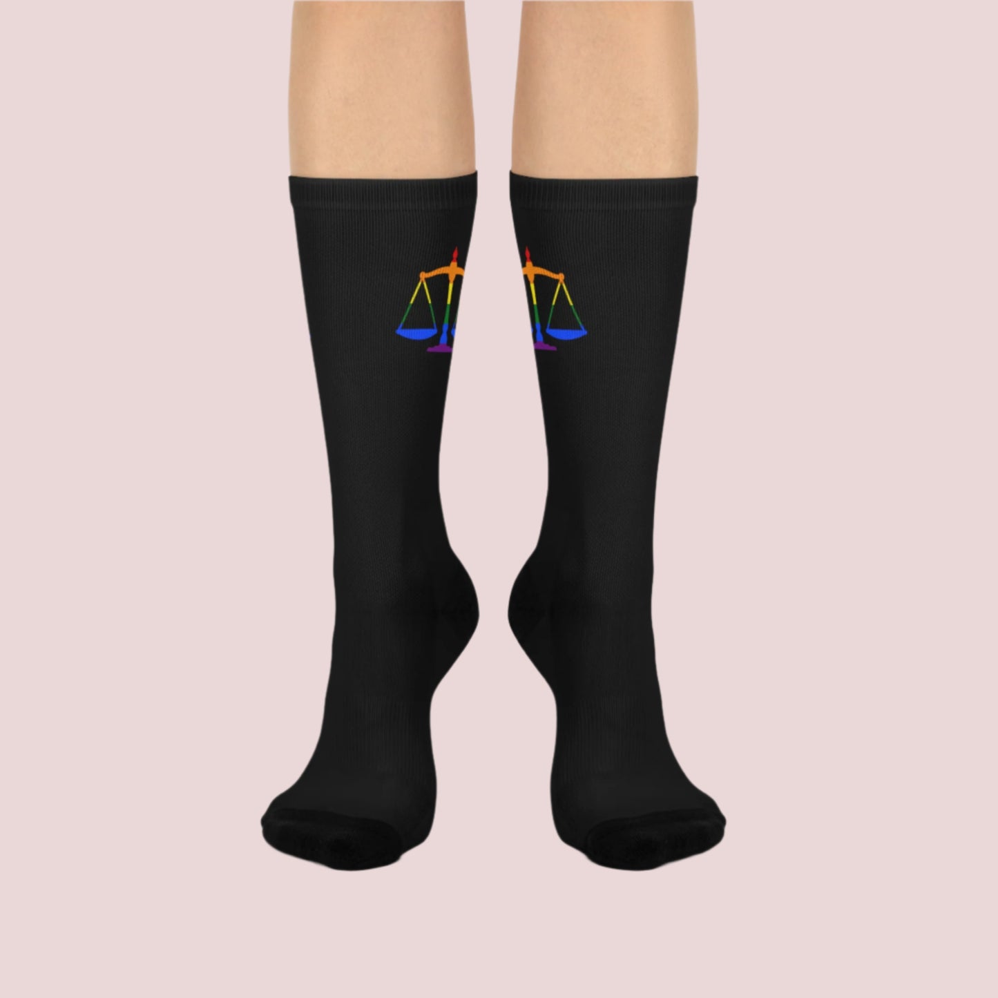 A pair of black crew socks featuring the rainbow justice scales design at the cuff.