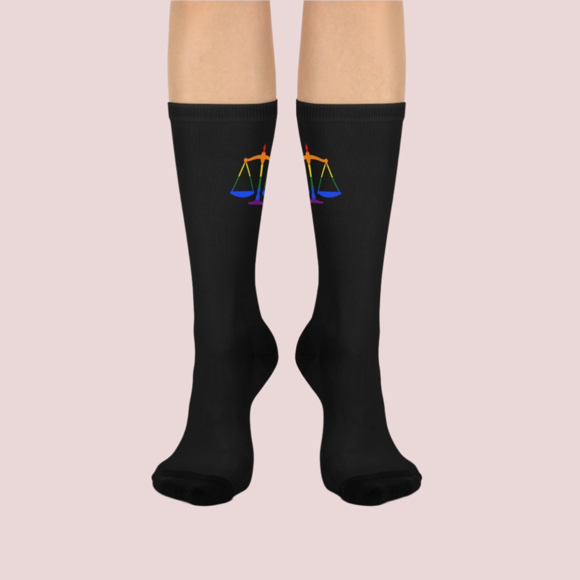 A pair of black crew socks featuring the rainbow justice scales design at the cuff.