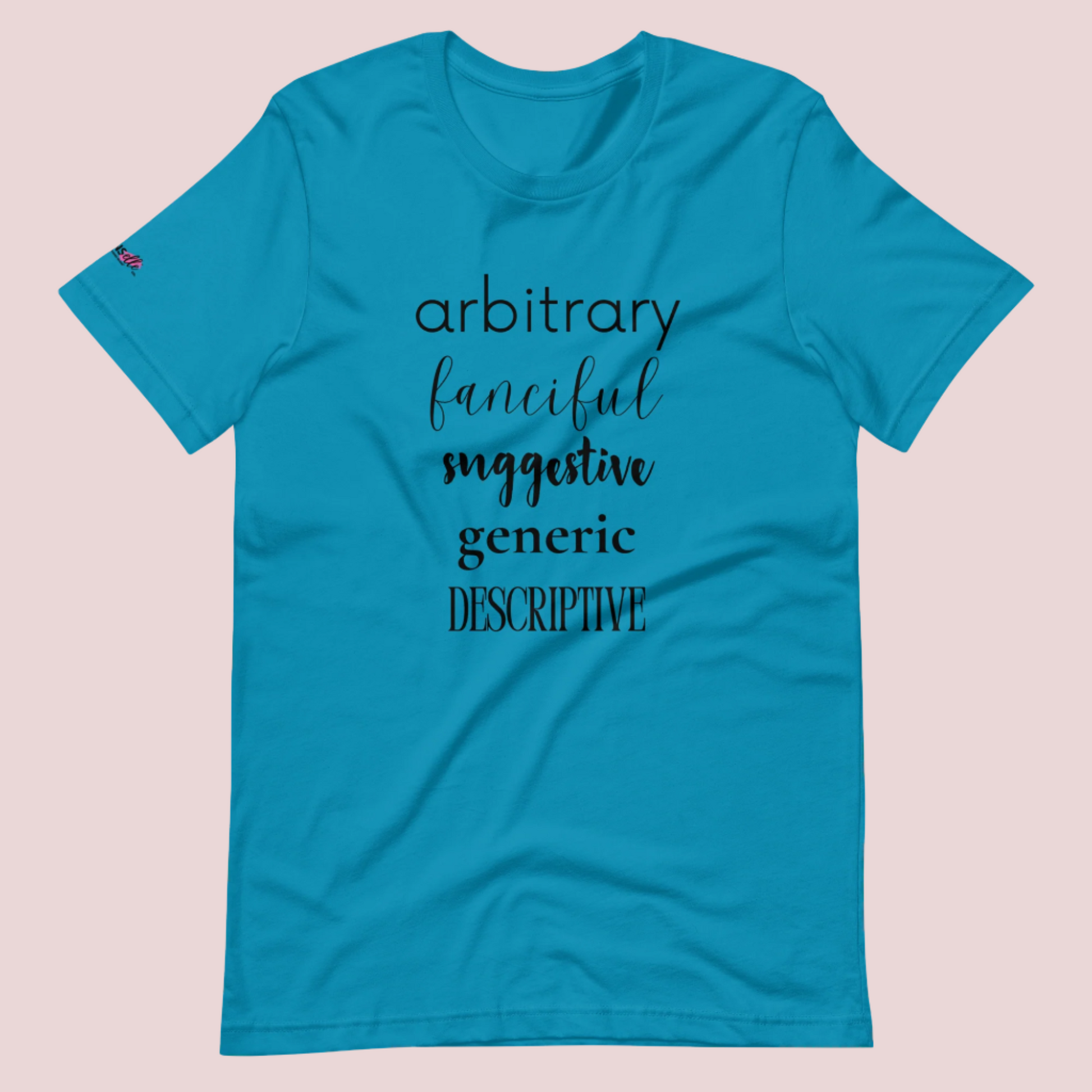 An aqua blue roundneck tee featuring the words "arbitrary", "fanciful", "suggestive", "generic", and "descriptive" in different font styles, with the counsellecollection logo on a sleeve.