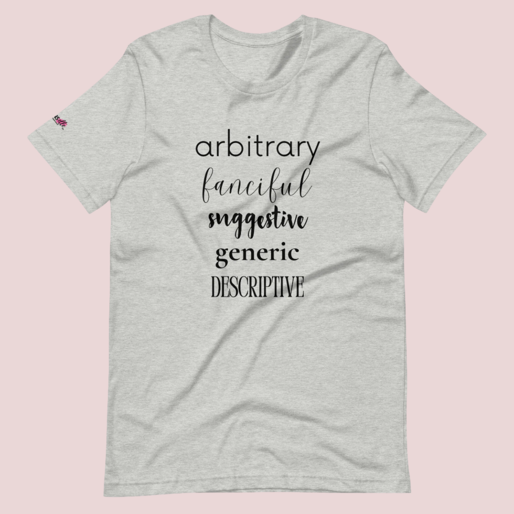 A heather grey roundneck tee featuring the words "arbitrary", "fanciful", "suggestive", "generic", and "descriptive" in different font styles, with the counsellecollection logo on a sleeve.