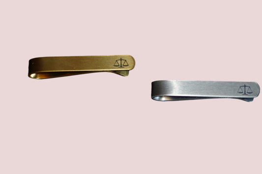 Two tie clips in gold and silver featuring a detailed justice scales emblem. 